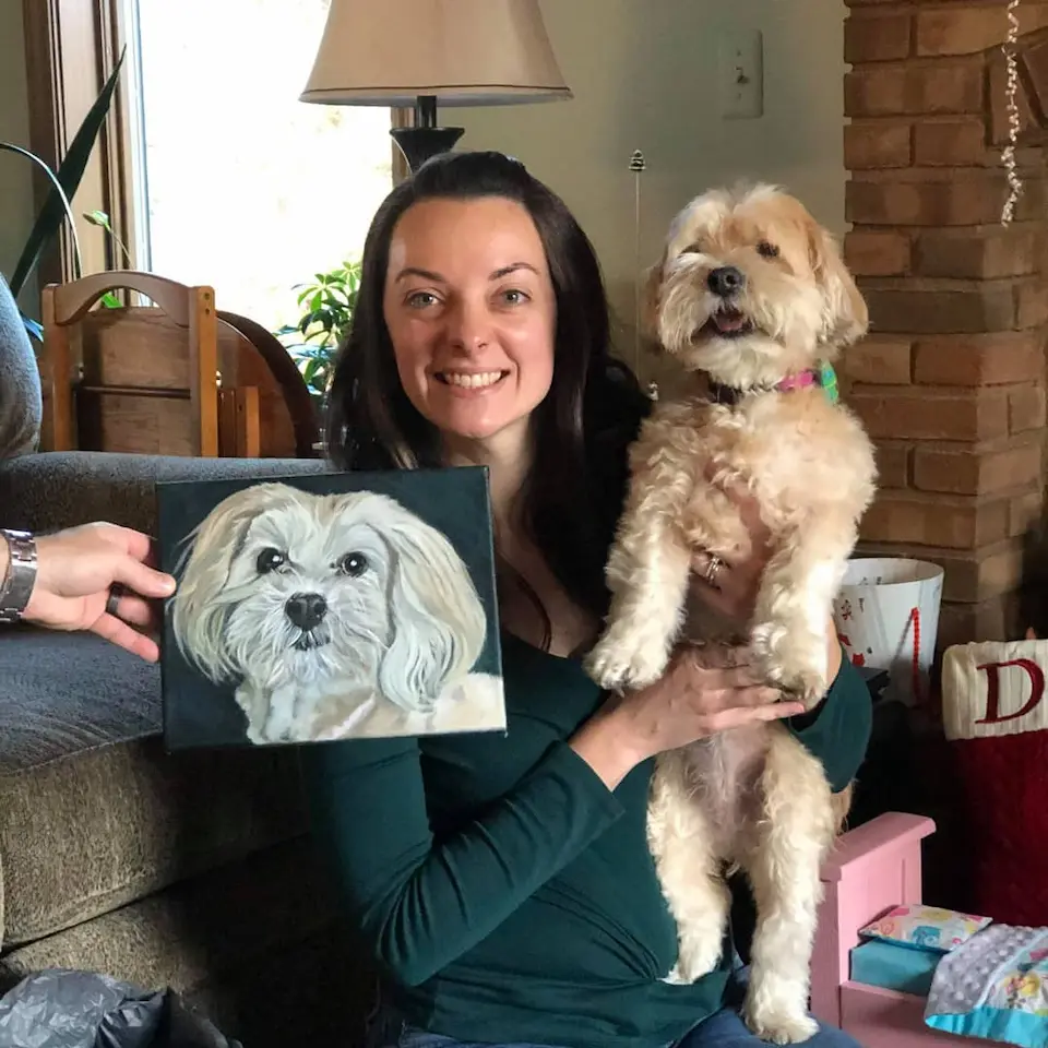 Happy customer holding her dog with a completed portrait